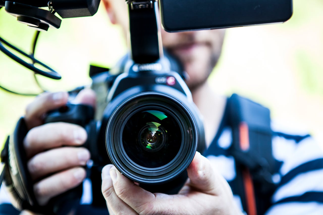 services-01 A close-up shot of a cameraman filming, focusing on the camera lens and equipment.