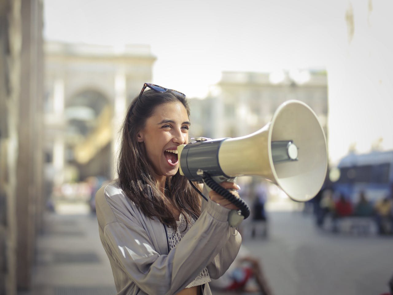 services-02 Cheerful young woman in a casual outfit shouting into a megaphone on a sunny day.