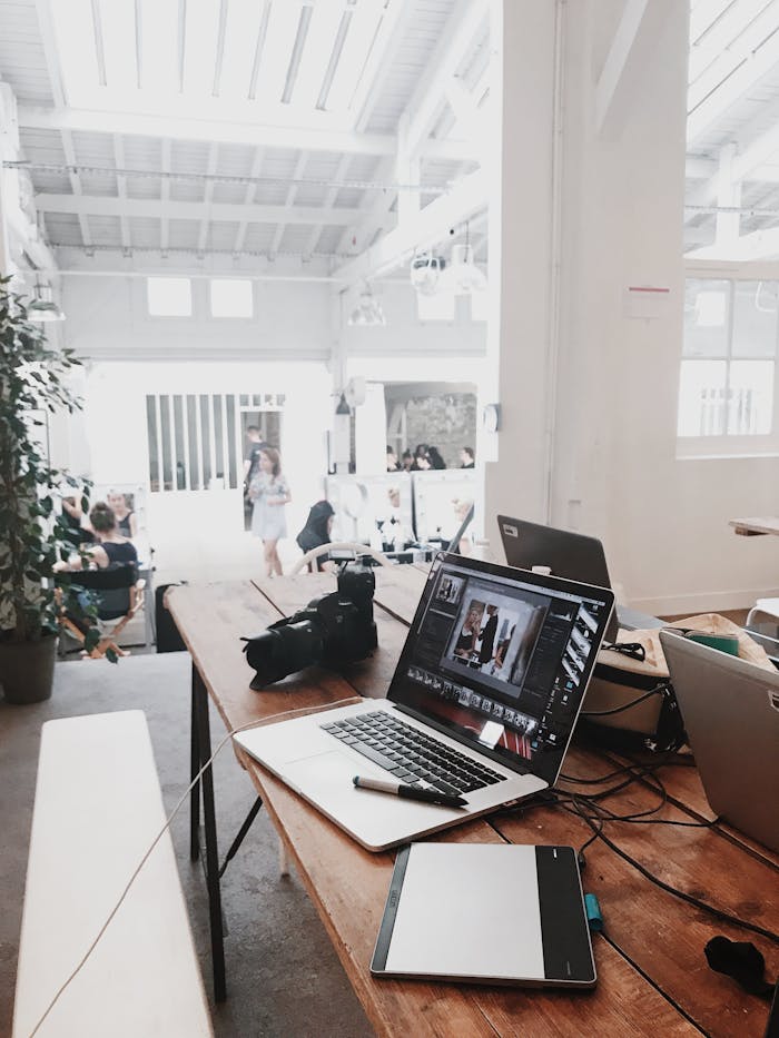 our-story A bright, modern workspace featuring laptops, a camera, and a drawing tablet in an indoor office.