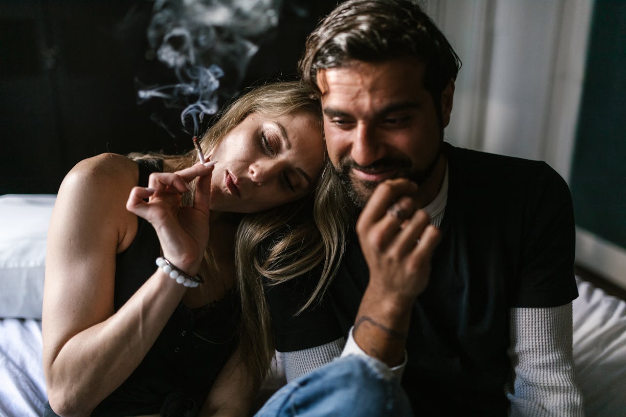 A couple enjoying a relaxed moment indoors while smoking a joint together.